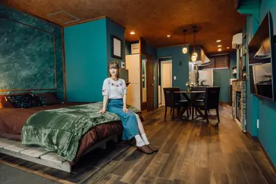 a woman sitting on a bed in a room at Villa Boushu KURAMAE in Tokyo