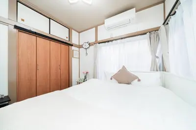 a bedroom with a large white bed and windows at \u938c\u5009\u56db\u4e01\u76ee in Tokyo