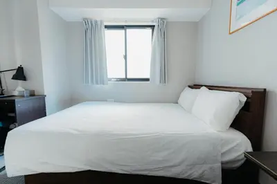 a white bed in a room with a window at Hotel LiVEMAX Shiodome in Tokyo