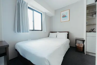 a bedroom with a large white bed and a window at Hotel LiVEMAX Shiodome in Tokyo