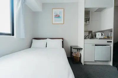 a bedroom with a white bed and a small kitchen at Hotel LiVEMAX Shiodome in Tokyo