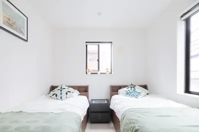 two beds in a room with white walls and windows at MEET IN SKYtree in Tokyo