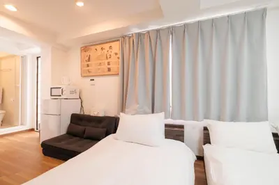 a hotel room with two beds and a chair at Hearty Stay Ikebukuro in Tokyo