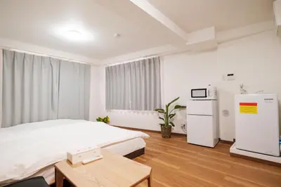 a bedroom with a bed and a refrigerator and a table at Hearty Stay Ikebukuro in Tokyo