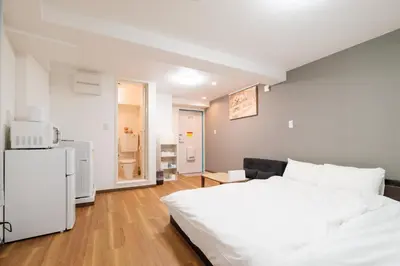 a bedroom with a white bed and a refrigerator at Hearty Stay Ikebukuro in Tokyo