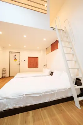 a bedroom with a white bed and a spiral staircase at Hearty Stay Ikebukuro in Tokyo