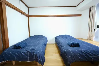 two beds in a room with blue sheets at AMs house 5 min to Ikebukuro 13 min to Shinjuku Station 19 min to Shibuya Station in Tokyo
