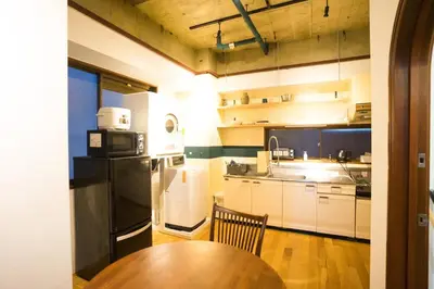 a kitchen with a wooden table and a black refrigerator at AMs house 5 min to Ikebukuro 13 min to Shinjuku Station 19 min to Shibuya Station in Tokyo