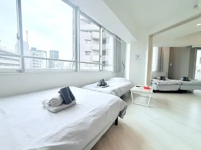 two beds in a room with a large window at Terrace Tokyo Otsuka North in Tokyo