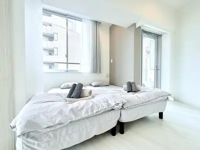 a white bedroom with a large bed with two pillows at Terrace Tokyo Otsuka North in Tokyo