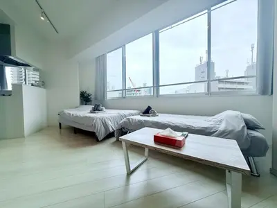 a room with two beds and a table and windows at Terrace Tokyo Otsuka North in Tokyo