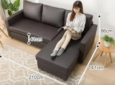 a woman sitting on a black couch in a living room at Cozy Room near Shinjuku Shibuya Ikebukuro in Tokyo