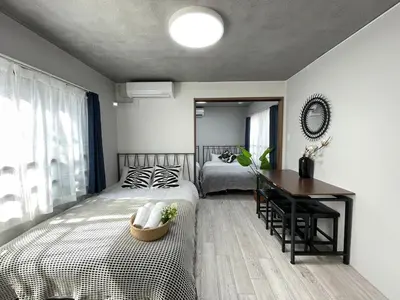 a bedroom with two beds and a table and a desk at Comma House Otsuka 3-2 in Tokyo