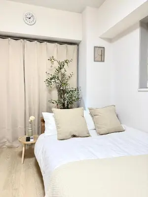 a bedroom with a white bed and a clock on the wall at MIKASA guesthouse2 in Tokyo