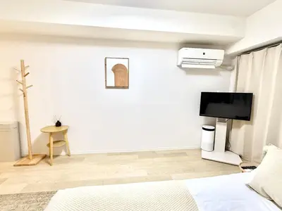 a white bedroom with a bed and a tv at MIKASA guesthouse2 in Tokyo