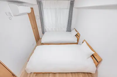 two beds in a small room with a window at \u30bf\u30b9\u30ad\u30b9\u30de\u30fc\u30c8\u6c60\u888b\u4e00\u53f7\u9928Tasuki Smart Ikebukuro1 in Tokyo