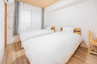 two beds in a small room with a window at \u30bf\u30b9\u30ad\u30b9\u30de\u30fc\u30c8\u6c60\u888b\u4e00\u53f7\u9928Tasuki Smart Ikebukuro1 in Tokyo