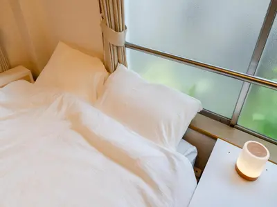 a bed with white sheets and a cup on a table at Ikebukuro-Shinjuku-5min Zoshigaya Sta-Easy train access to Shinjuku and Shibuya in Tokyo