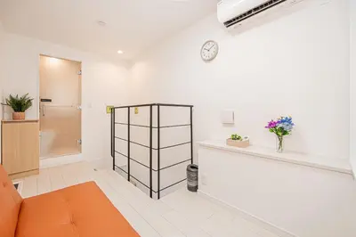 a living room with an orange couch and a clock on the wall at Japan House Edogawabashi Retaw Hills Aprtment in Tokyo