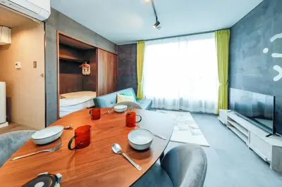 a dining room with a wooden table and a couch at Flat K Plum Umegaoka by Tranova in Tokyo