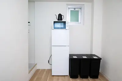 a room with a refrigerator and two trash cans at Yamamoto building by Tranova in Tokyo