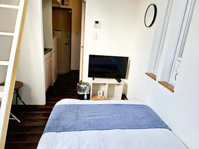 a bedroom with a bed and a tv on a wall at \u4e2d\u91ce\u30b7\u30a8\u30b9\u30bf\u30d7\u30ea\u30e0\u30e9 in Tokyo
