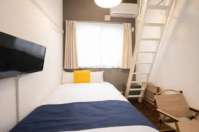 a bedroom with a bed with a television and a ladder at \u4e2d\u91ce\u30b7\u30a8\u30b9\u30bf\u30d7\u30ea\u30e0\u30e9 in Tokyo