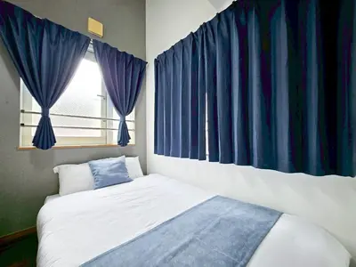 a bed in a room with blue curtains and a window at \u4e2d\u91ce\u30b7\u30a8\u30b9\u30bf\u30d7\u30ea\u30e0\u30e9 in Tokyo