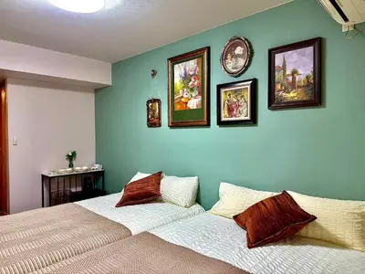 a bedroom with two beds and pictures on the wall at G84 Shinjuku center 5 mins to Station, Max 3-\u65b0\u5bbf\u6700\u4e2d\u5fc3 \u6771\u65b0\u5bbf\u7ad95\u5206 \u76f4\u8fbe\u65b0\u5bbf \u6d89\u8c37 \u8868\u53c2\u9053 \u6c60\u888b \u4e0a\u91ce \u4ee3\u4ee3\u6728 \u94f6\u5ea7 \u539f\u5bbf in Tokyo