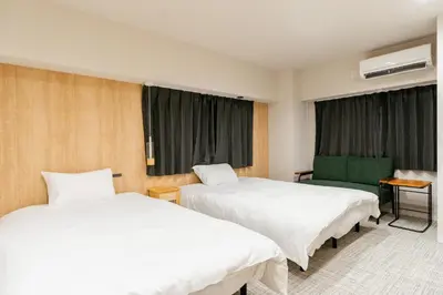 a hotel room with two beds and a green chair at Humming Kinshicho 303-202-301 - Vacation STAY 18969 in Tokyo