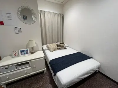 a small bedroom with a bed and a night stand at Imperial Tateishi in Tokyo