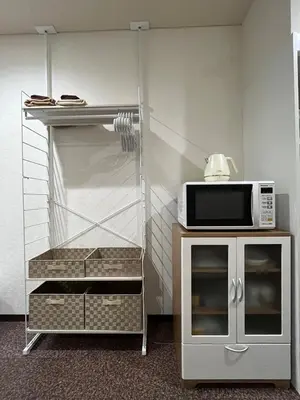 a microwave on top of a stand with a counter with a kitchen at Imperial Tateishi in Tokyo