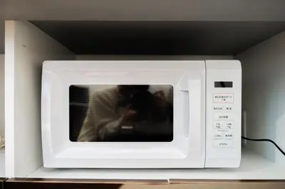 a white microwave oven with a person sitting inside at Nine Lane Nippori in Tokyo
