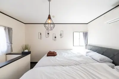 a bedroom with a large white bed and a chandelier at Tune Inn Residence Nihonbashi in Tokyo