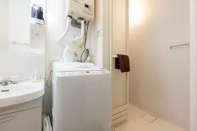 a small bathroom with a washing machine and a sink at Tune Inn Residence Nihonbashi in Tokyo