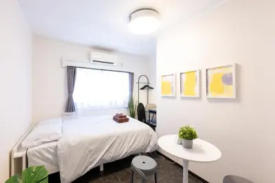 a white bedroom with a bed and a table at Tune Inn Residence Nihonbashi in Tokyo