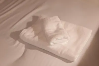 a white towel sitting on top of a bed at SATELLITE HOTEL Roppongi 2nd \u30b5\u30c6\u30e9\u30a4\u30c8\u30db\u30c6\u30eb\u516d\u672c\u67282nd in Tokyo