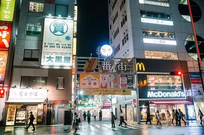 a group of people crossing a busy city street at night at Akabane Nishi Masuda House in Tokyo