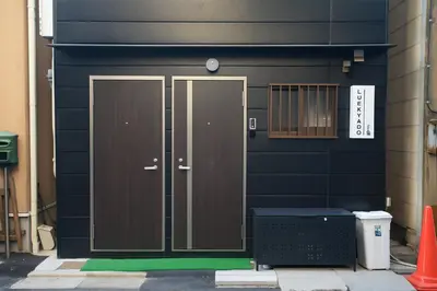 a black house with a brown door with a green floor at 101 Convenient Ueno Lucky Yado in Tokyo