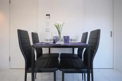 a dining room table with black chairs and a vase of flowers at HJ PLACE Takanawa by Tranova in Tokyo