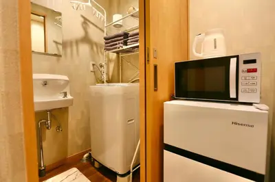 a small kitchen with a microwave on top of a refrigerator at 201 Modern Ueno House Lucky Yado in Tokyo