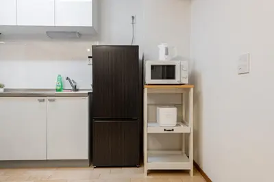 a kitchen with a black refrigerator and a microwave at \u304b\u3064\u3089306 in Tokyo