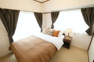 a bedroom with a large bed in front of windows at \u5bdb\u6c38\u5bfa\u5742\u30cf\u30a4\u30e0 501 in Tokyo