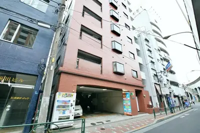 a pink building with a garage on a city street at \u5bdb\u6c38\u5bfa\u5742\u30cf\u30a4\u30e0 501 in Tokyo