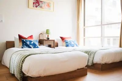 two beds in a room with a window at Mi-HOTEL MIYA SHINJUKU in Tokyo