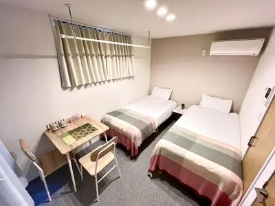 a small room with two beds and a table at \u6c60\u888b \u5de3\u9d28 YMhotel \u6700\u592718\u540d\u53ef-ikebukuro sugamo- in Tokyo