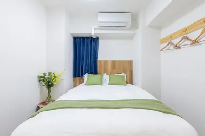 a bedroom with a large white bed with green pillows at 3 bedrooms, 5-minute walk to Shinjuku City Center, Isetan department store , max 7 people in Tokyo