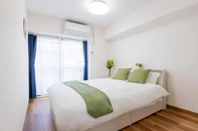 a bedroom with a large white bed with green pillows at 3 bedrooms, 5-minute walk to Shinjuku City Center, Isetan department store , max 7 people in Tokyo