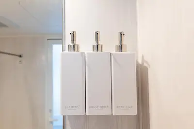 a group of three white soap dispensers on a wall at LIVCITY Kinshicho 601 in Tokyo