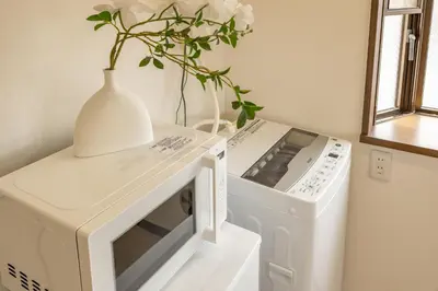 a microwave oven with a vase on top of it at 2BR Apartment Only 2 Stops to Shinjuku Includes Baby Essentials & Luggage Hold in Tokyo